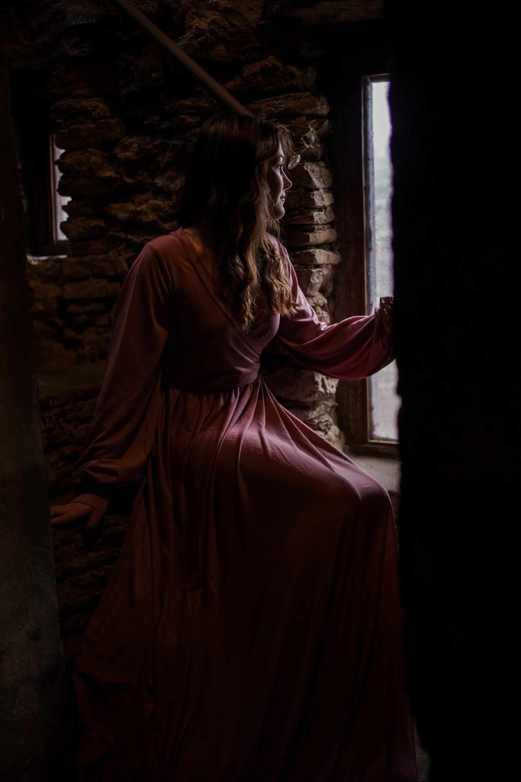 Loveland Castle Senior Session. Flowy dusty rose gown in the gardens. Sitting inside tower looking out window