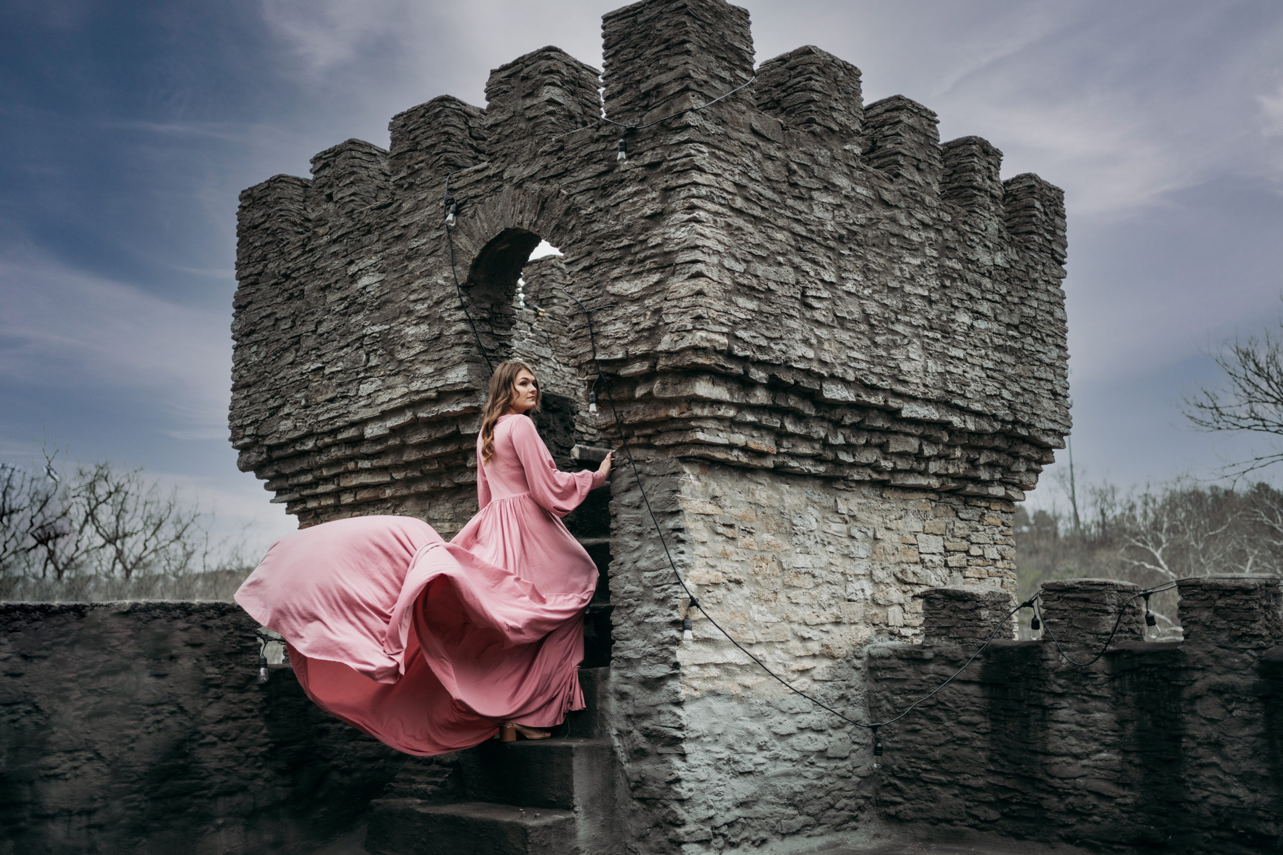 Loveland Castle Senior Session. Flowy dusty rose gown in the gardens. Standing in stone doorway at the tower
