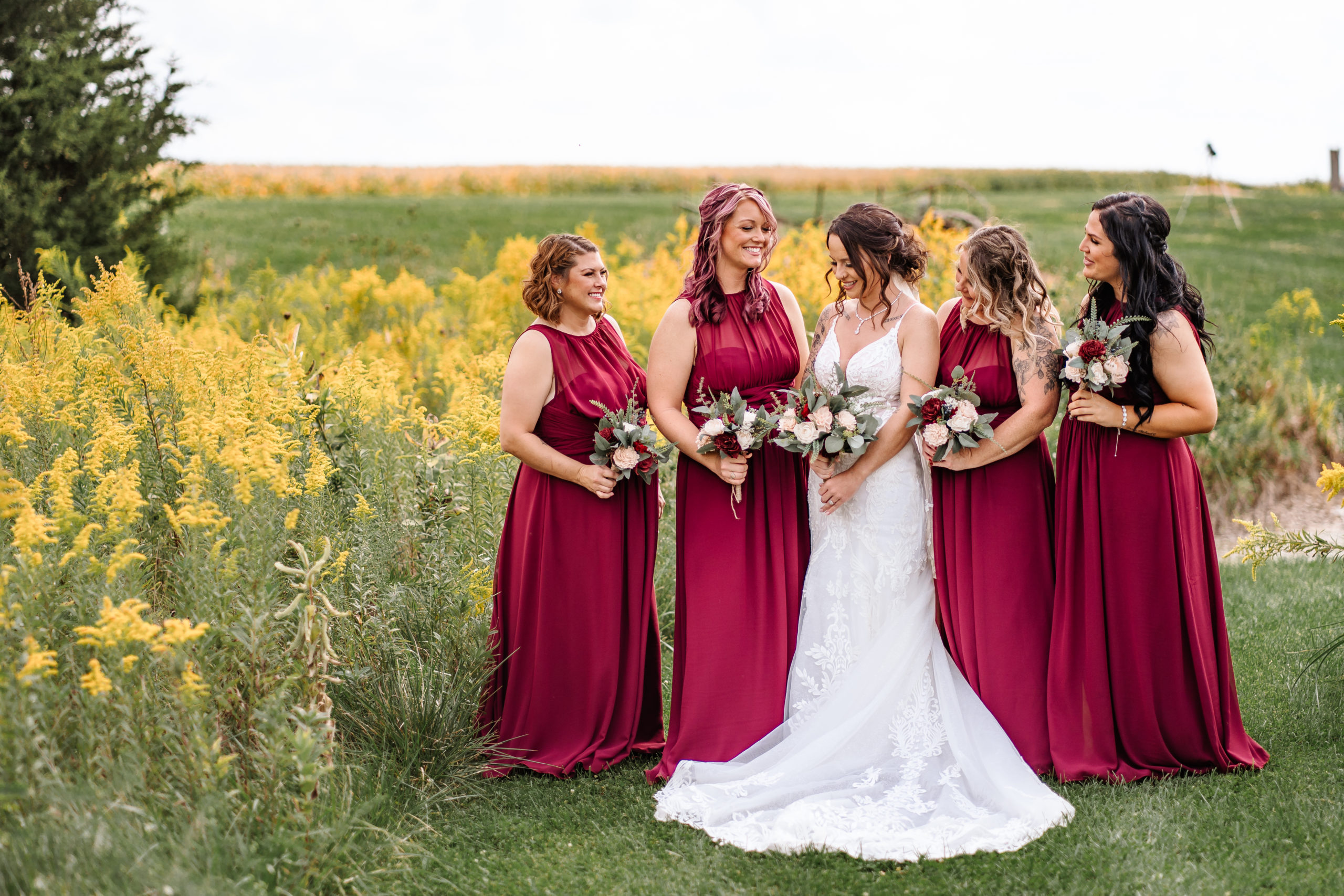 bride and bridesmaids standing together in a field of ragweed
