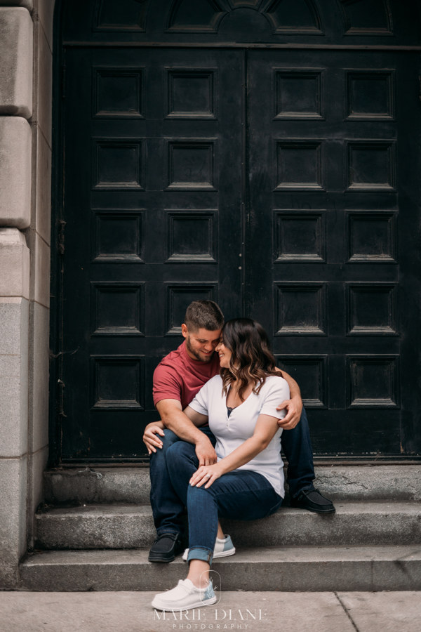 engagement session sitting on stone stairs in front of large door