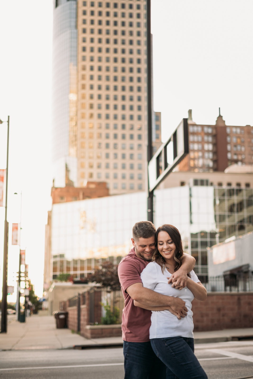 downtown cincinnati engagement couple in front of tall buildings at sunset
